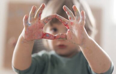 Un enfant tend ses mains pleine de peinture formant un rond