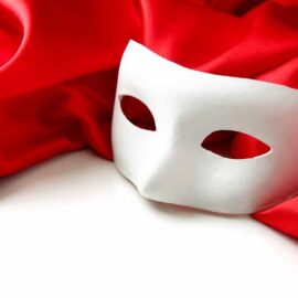 Masque blanc de théâtre posé sur un tissu rouge