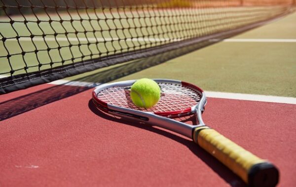 Raquette et balle de tennis posées sur le sol du court de tennis