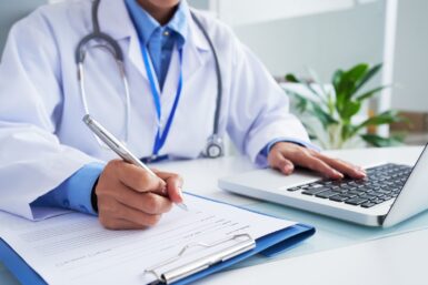 Médecin vérifiant les informations dans un programme informatique avant de remplir la fiche médicale